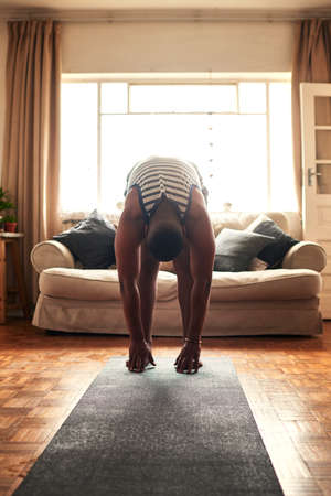 Exercise doesnt drain you, it energizes you. Shot of a young man practising yoga at home during the...