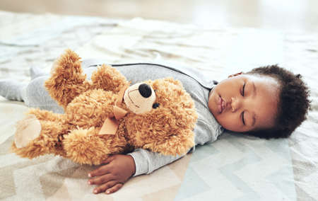 Theres nothing more precious than this moment. Shot of a baby boy asleep with his teddy bear in his...