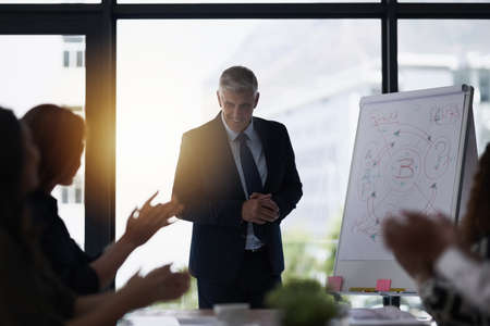 Theyre loving his ideas. Shot of a team of silhouetted businesspeople attending a meeting in the boardroom.の写真素材