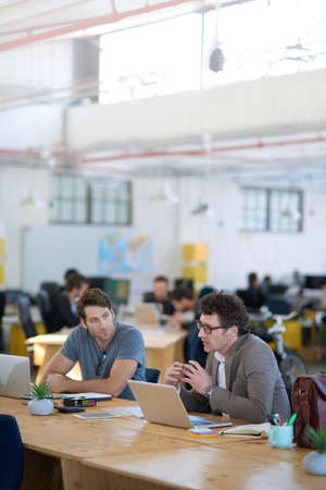 Talking through their creative process. Shot of two colleagues talking together while working on...