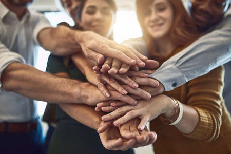 Success belongs to those who grab it. Shot of a group of colleagues joining their hands in...