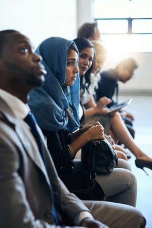 Only the best will pass the test. Shot of a group of well-dressed businesspeople seated in line...