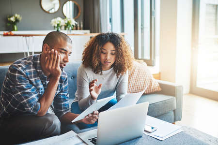 Our finances need an overhaul. Shot of a young couple using a laptop and digital tablet while...