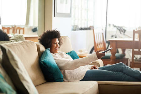 When you find an entire season of your favorite show. Shot of a young woman relaxing on the sofa at...