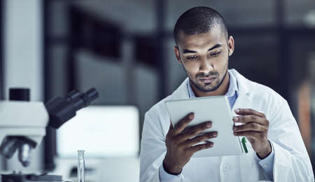 The use of electrical medical records increases. Shot of a scientist recording his findings on a digital tablet.の写真素材