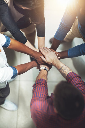 Taking it to the top together. Cropped shot of a work group joining hands in solidarity.
