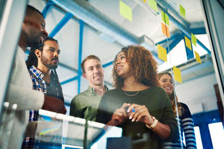 It takes people to make success a reality. Shot of colleagues having a brainstorming session with sticky notes at work.の写真素材