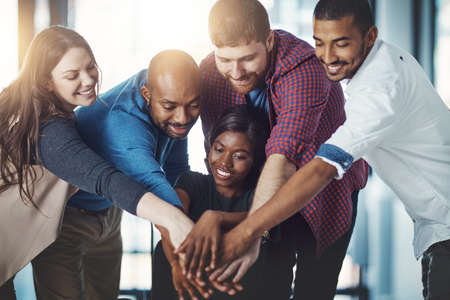 Sticking together in the name of success. Shot of a young work group joining hands in solidarity.の写真素材
