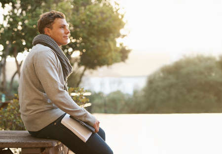 So much to achieve. Shot of a thoughtful young male student leaning on a campus bench.