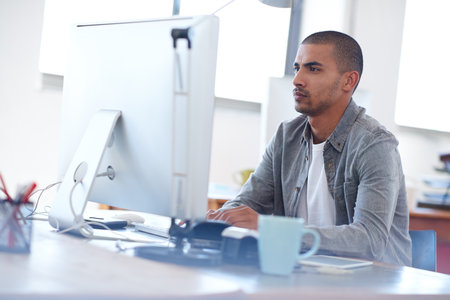 Youthful focus on professional solutions. Young creative man at work on his pc in a bright open...
