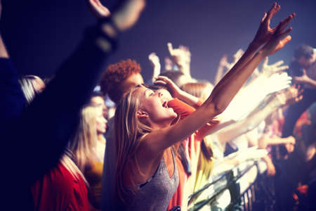 Enjoying the music. A group of people standing with their arms raised at a concert.