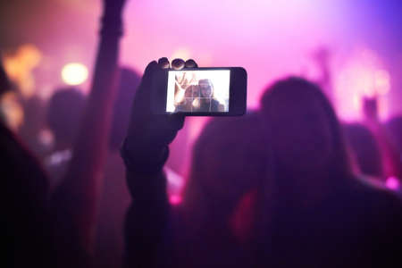 Shot of a fan filming a concert on their camera. This concert was created for the sole purpose of this photo shoot, featuring 300 models and 3 live bands. All people in this shoot are model released.の写真素材