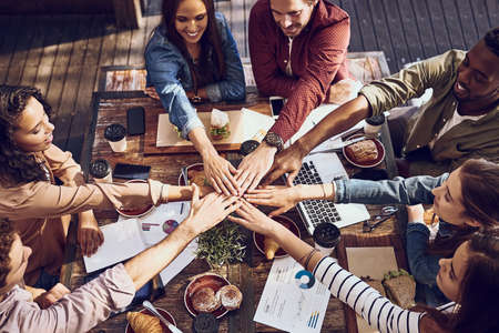 Food inspires everyone. High angle shot of a group of creative workers piling their hands while out on a business lunch.の写真素材