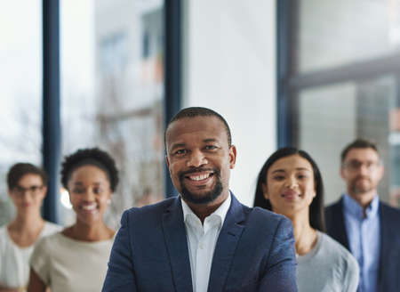 Positive leaders create productive teams. Cropped shot of a group of businesspeople standing in the office.の写真素材