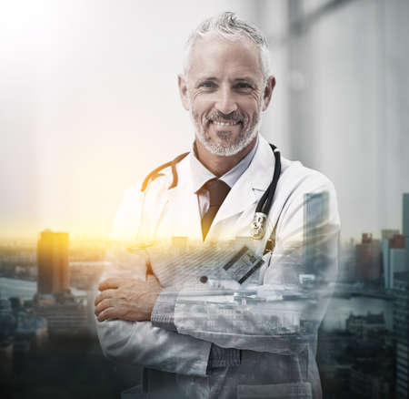 Your health is my happiness. Multiple exposure shot of a mature doctor superimposed on a cityscape.の写真素材