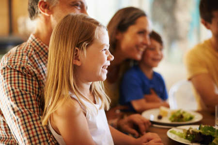 Granddads lap is prime position. Shot of a little girl sitting on her grandfathers lap at dinner...