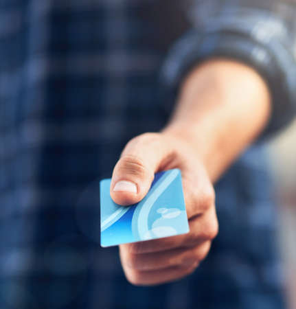 Swipe it on my card. Shot of a man holding out a credit card.の写真素材