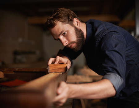 Since opportunity didnt knock, he decided to build a door. Shot of a young artisan working intently in his workshop.の写真素材