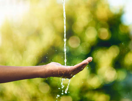Pure and precious to nature. Shot of hands held out to catch a stream of water outside.の写真素材