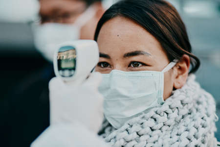 The quicker way to get results. Shot of a young woman getting her temperature taken with an infrared...