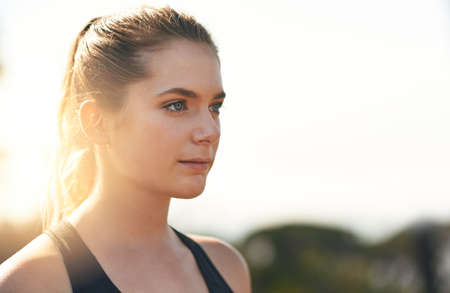 Set your mind to fit. Shot of a young runner training outdoors.の写真素材