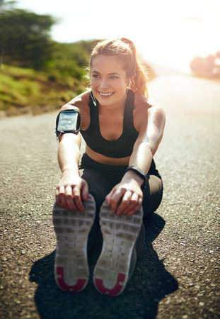 Stay safe and stretch those muscles. Shot of a young woman stretching before her run outdoors.
