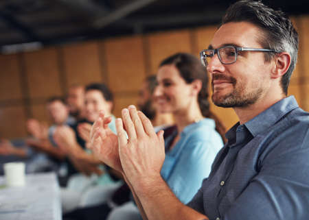 The creative process. Shot of a group of colleagues clapping together at a table in an office.