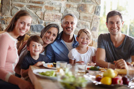 Loving, caring, sharing - this is family. A portrait of a happy multi-generational family having a meal together outdoors.の写真素材
