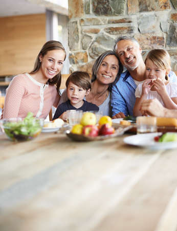 Treasured moments with the grandkids. A portrait of a happy multi-generational family sitting at a table and having lunch together.の写真素材
