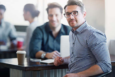 Taking care of business, even over coffee. Portrait of a two colleagues having a talk over coffee in an office in an office.の写真素材