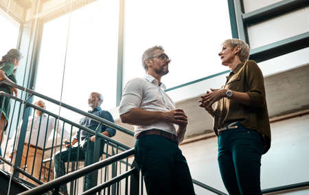 Great ideas come from casual conversations. Shot of two businesspeople talking to each other while standing on a stairwell.の写真素材