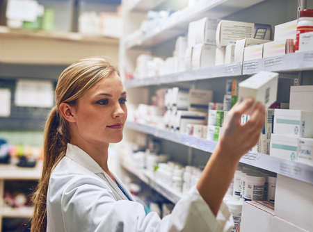 I know exactly the medication thatll help you. Shot of a pharmacist looking at medication on a shelf.の写真素材