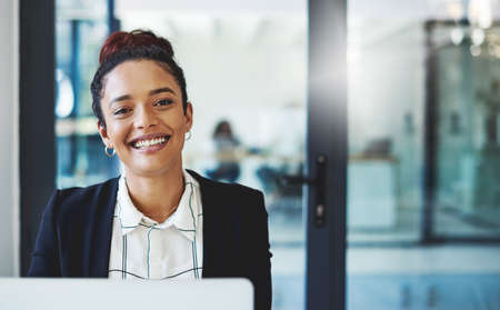 Reaching my goals one workday at a time. Shot of a young businesswoman using a laptop in a modern...