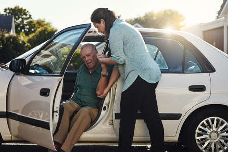 Ill be the support you need. Shot of a woman helping her senior father out the car.