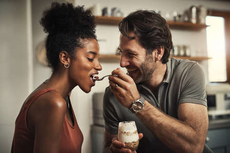 I know its your favourite. Cropped shot of an affectionate middle aged man feeding his wife dessert in their kitchen at home.の写真素材