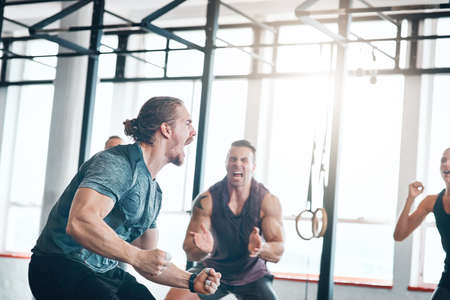 Turn your dreams into reality. Shot of a fitness group celebrating a victory at the gym.の写真素材