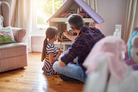 Giving her dolls a place to call home. Shot of a little girl playing with a dollhouse at home.の写真素材