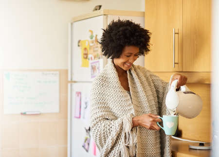 The freshest way to start the day. Shot of a young woman making a cup of tea at home in the morning.の写真素材