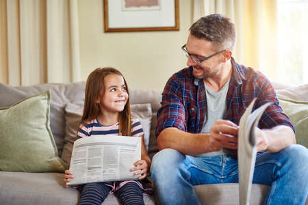 Being your parent is my favourite job. Shot of a father and daughter reading the newspaper.の写真素材