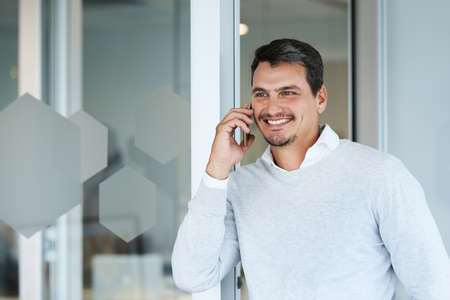 Hes always on call with success. Shot of a young businessman talking on a cellphone in an office.