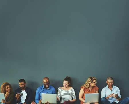 Connecting while we are connected. Studio shot of a diverse group of people social networking...