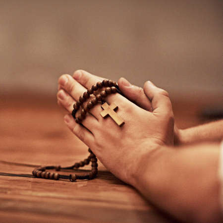 Hes always there to answer your prayers. Cropped shot of a man holding a rosary and praying.の写真素材
