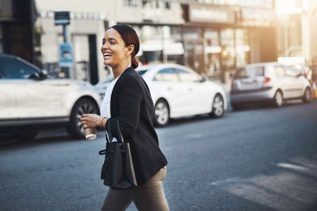 Off to meet a client around town. Shot of a young businesswoman walking in the city.の写真素材