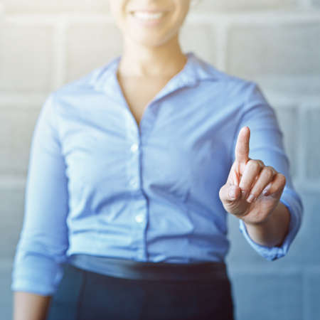 Its work. Cropped shot of a businesswoman connecting to a user interface with her finger.の写真素材