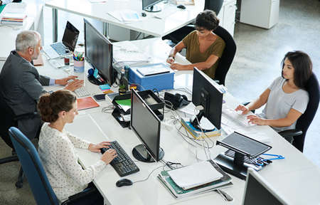 Making success one project at a time. Shot of a group of coworkers sitting at their workstations in an office.の写真素材