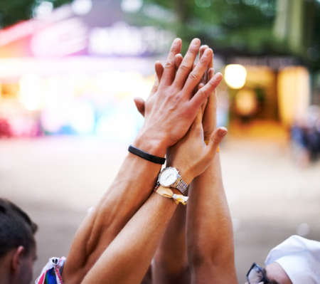 Lets do it. Cropped shot of a group of friends high-fiving at an outdoor festival.の写真素材