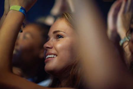 Shot of a young woman in a crowd at a concert. This concert was created for the sole purpose of this photo shoot, featuring 300 models and 3 live bands. All people in this shoot are model released.の写真素材