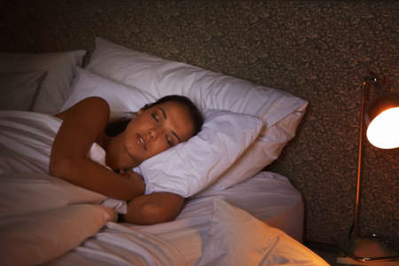 Snug as a bug. Shot of an attractive young female sleeping in the dark.の写真素材