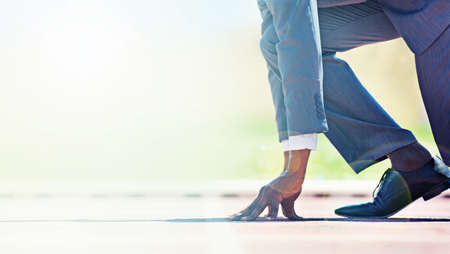 Run towards your business goals. A young businessman at the starting line of a race track.の写真素材