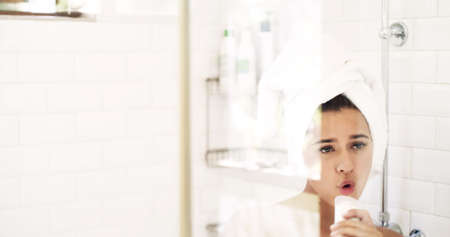 Time to debut a new you. Shot of an attractive young woman singing while going through her morning beauty routine at home.の写真素材